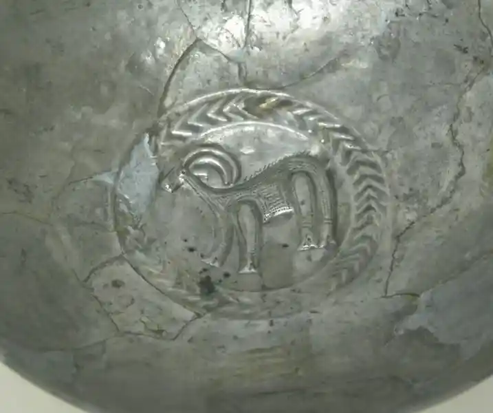 A metal dish with an antelope inside a circle